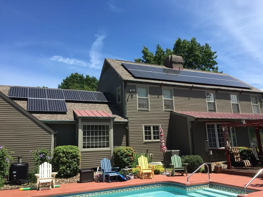 Two-story home with solar on the main roof and the wing, pool in the foreground