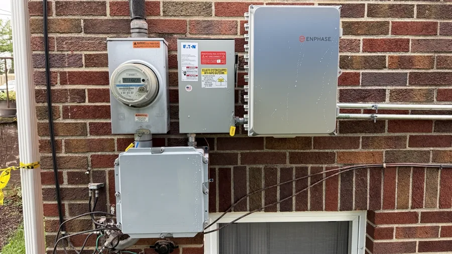 Utility meter and Enphase combiner and disconnect boxes mounted on a red brick wall