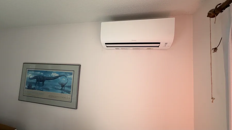 Wall-mounted ductless indoor head above a framed picture in a living room