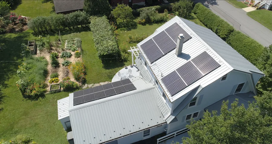 Aerial of a farmhouse with solar on its standing-seam metal roof and attached garage