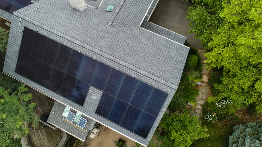 Aerial of a large shingle roof covered by a full black solar array