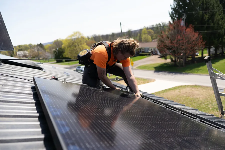 Sun Directed installer setting a solar module on a standing-seam metal roof