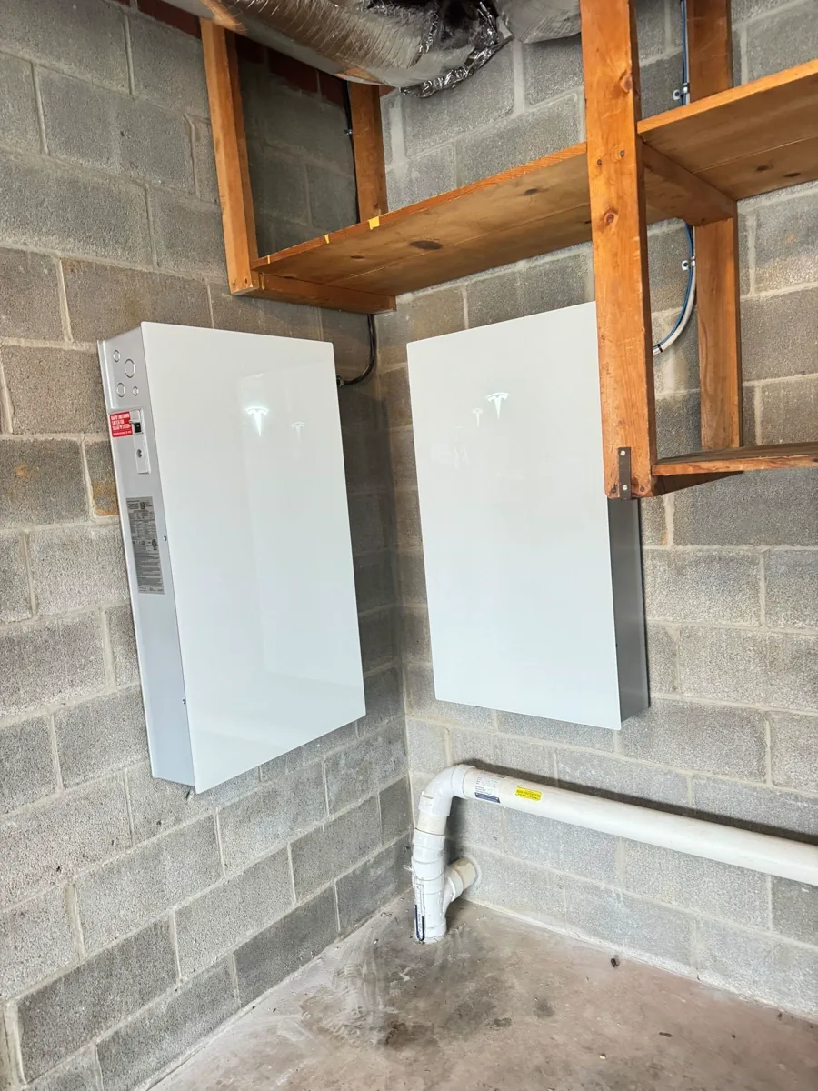 Tesla Powerwall 3 and backup gateway mounted on a basement cinder-block wall